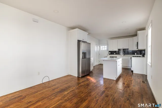a kitchen with white cabinets and wooden floor