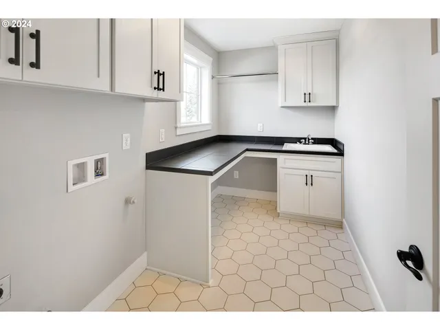 a kitchen with white cabinets a sink a stove and a window
