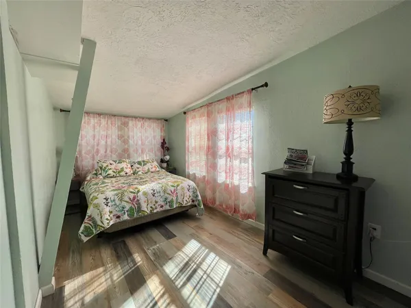 a bedroom with a bed and a lamp on dresser