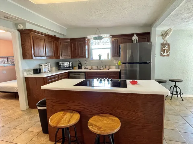 a kitchen with stainless steel appliances granite countertop a sink a stove a refrigerator a washer and dryer