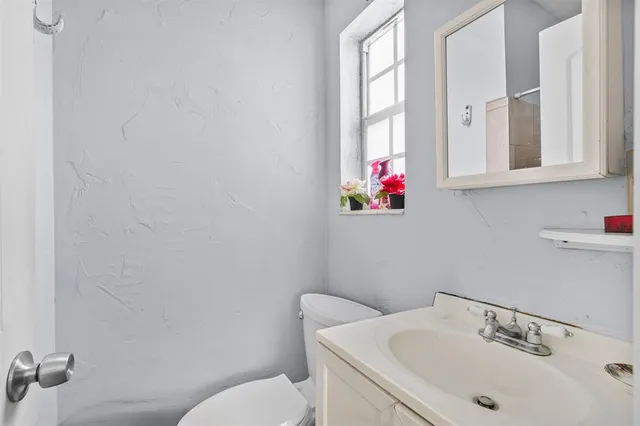 a bathroom with a sink mirror toilet and window