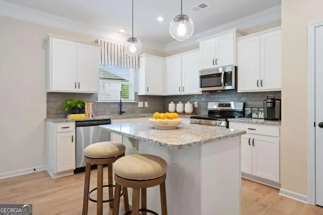 a kitchen with stainless steel appliances granite countertop a stove a sink a microwave a refrigerator and white cabinets
