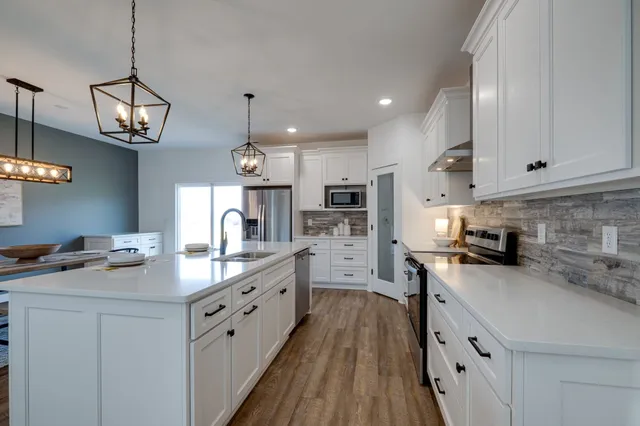 a kitchen with granite countertop white cabinets and stainless steel appliances