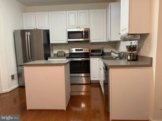 a kitchen with stainless steel appliances granite countertop a stove a refrigerator a sink a stove and a microwave