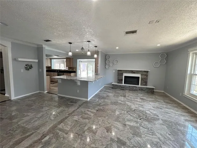 an empty room with kitchen and fireplace