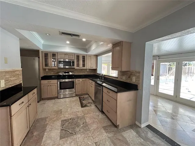 a kitchen with stainless steel appliances granite countertop a stove top oven a sink a counter space and cabinets