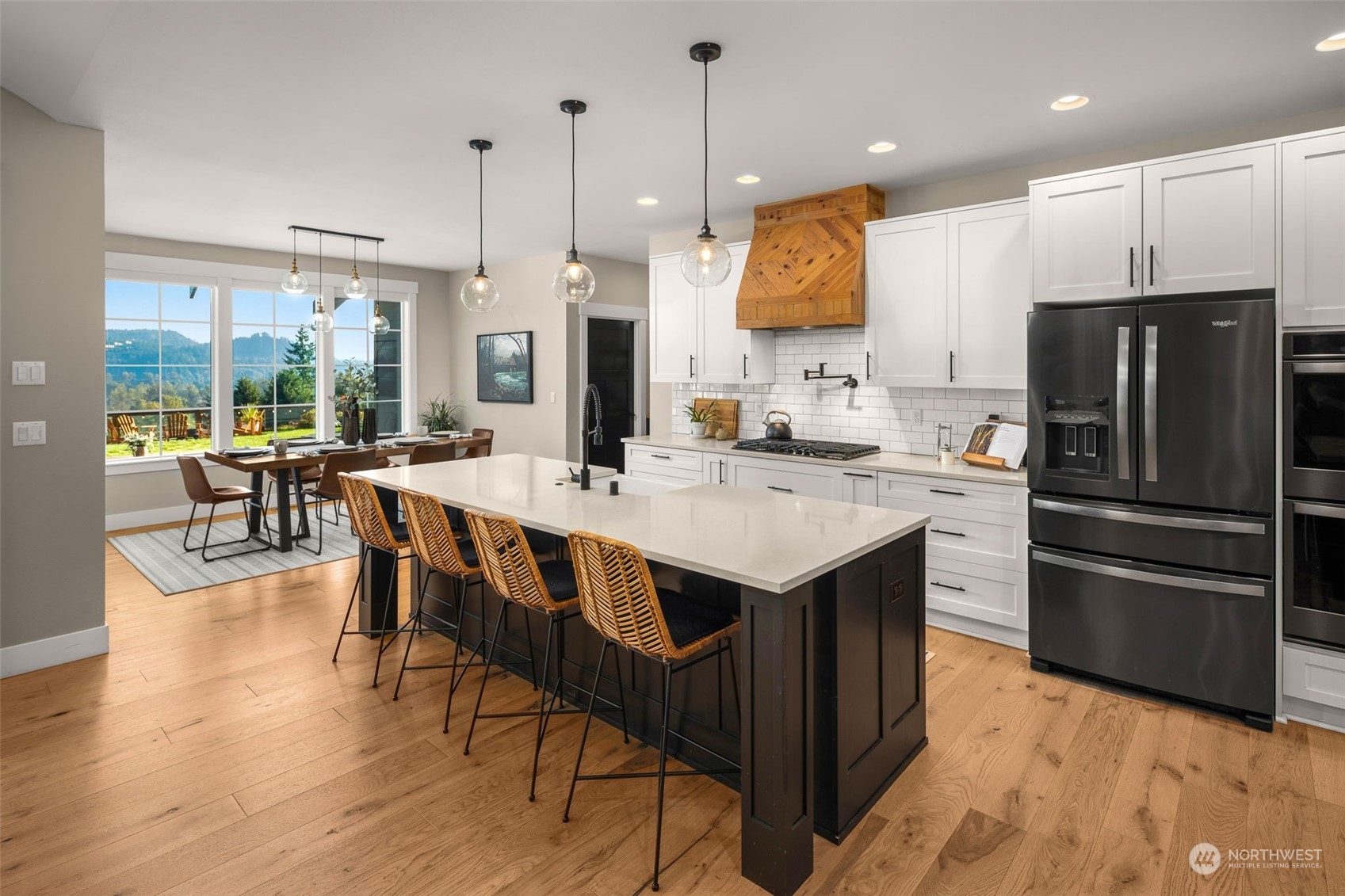 21468 Calhoun Road Monroe, WA 98272 - Photo 8 of 36 a kitchen with stainless steel appliances kitchen island granite countertop a kitchen island a stove a refrigerator a sink a dining table and chairs with wooden floor
