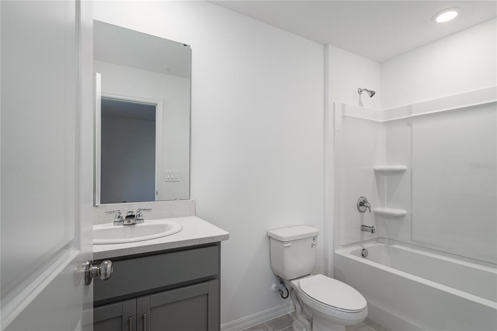 14052 Textile Run Parrish, FL 34219 - Photo 14 of 23 a bathroom with a granite countertop sink a toilet and shower