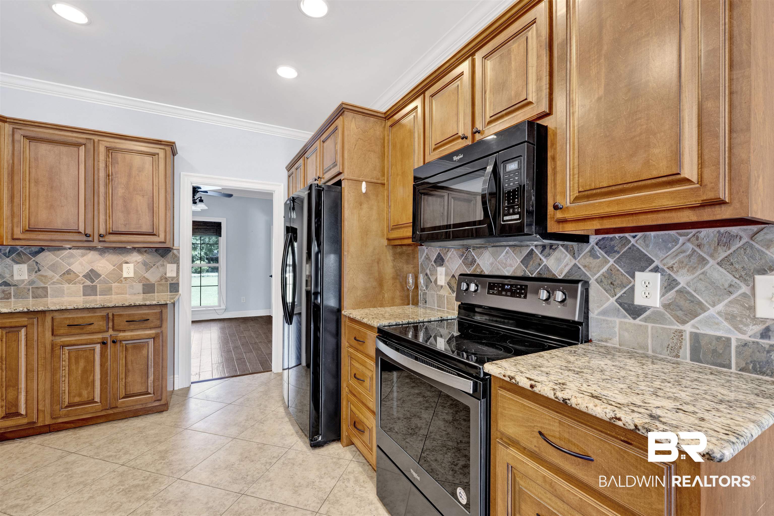 12944 Anna's Way Stapleton, AL 36578 - Photo 42 of 64 Kitchen featuring wood cabinetry, granite-style countertops, mosaic tile backsplash, black appliances, and recessed lighting