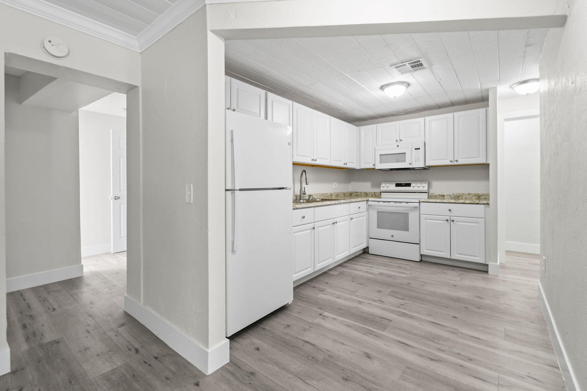 1301 West 25th Street Riviera Beach, FL 33404 - Photo 7 of 34 a kitchen with white cabinets and white appliances