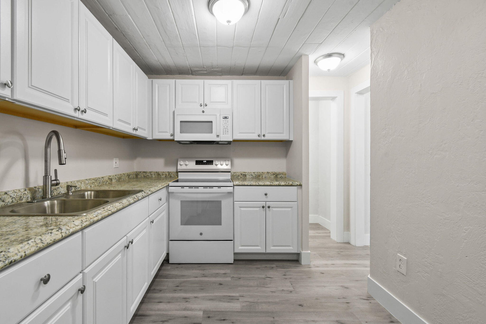 1301 West 25th Street Riviera Beach, FL 33404 - Photo 9 of 34 a kitchen with stainless steel appliances granite countertop a sink and cabinets with wooden floor
