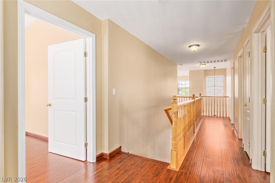 1477 Rancho Ridge Drive Henderson, NV 89012 - Photo 25 of 46 Rich hardwood floors guide you through this inviting upper-level hallway, boasting classic wood balusters and warm neutral tones.