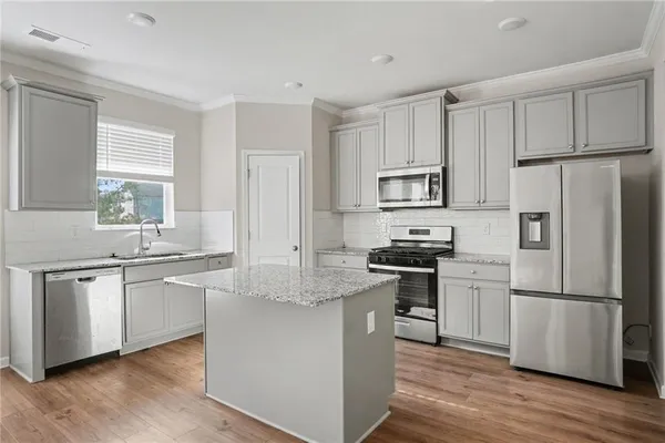 a kitchen with granite countertop white cabinets and stainless steel appliances