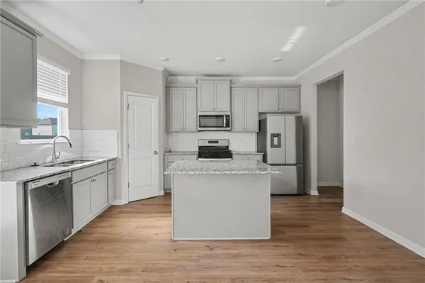 a kitchen with stainless steel appliances granite countertop a stove top oven a refrigerator a sink and dishwasher with wooden floor