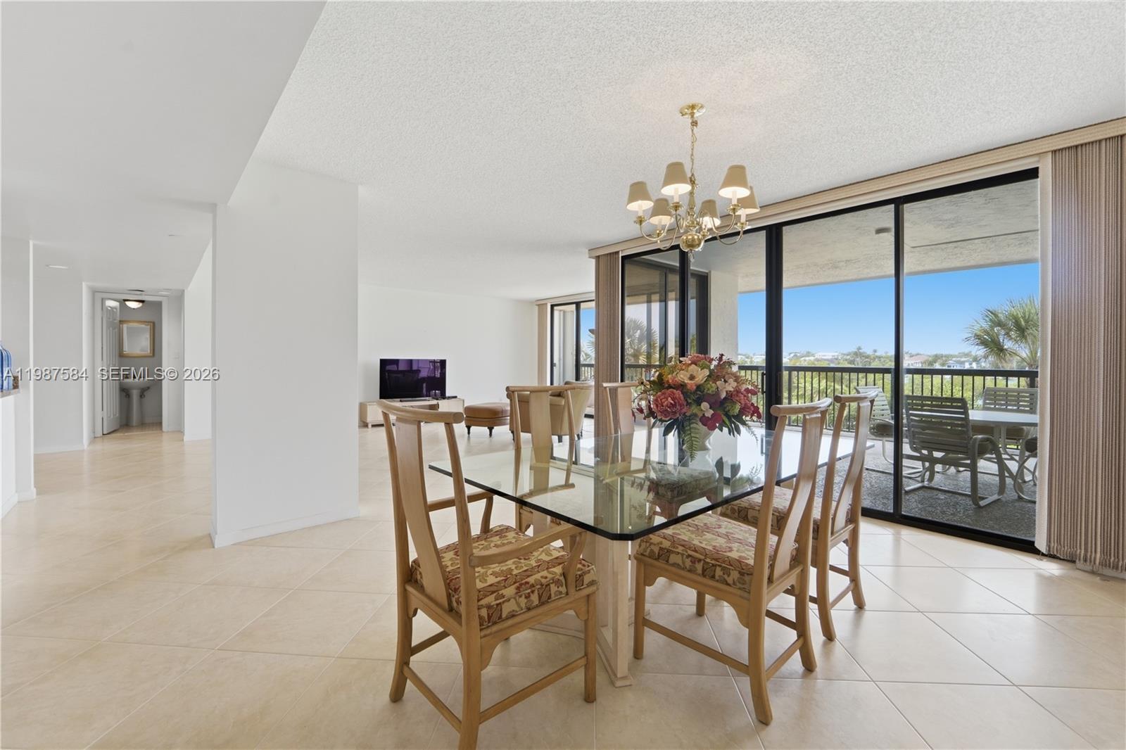 19670 South Beach Road, Unit B323 Tequesta, FL 33469 - Photo 17 of 57 a view of a dining room with furniture a chandelier and a large window