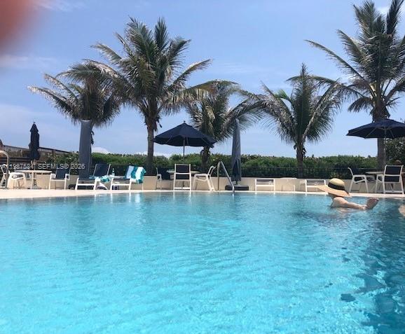 19670 South Beach Road, Unit B323 Tequesta, FL 33469 - Photo 9 of 31 a view of a swimming pool with a table and chairs under an umbrella