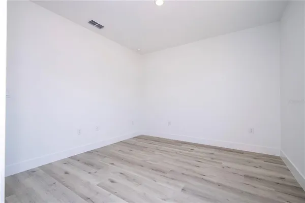a view of an empty room with wooden floor and closet