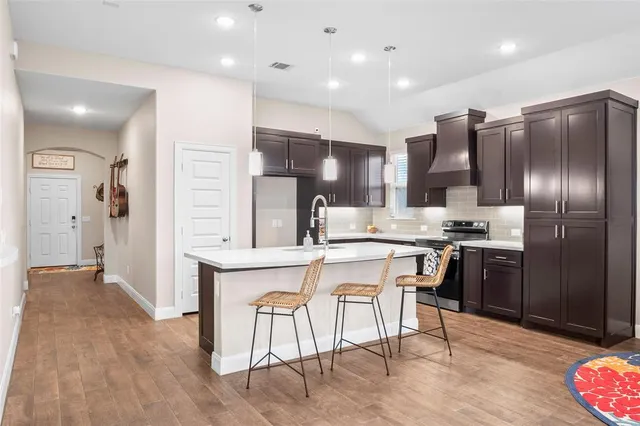 a kitchen with stainless steel appliances kitchen island granite countertop a refrigerator and a sink
