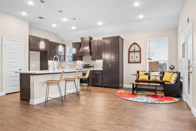 a kitchen with stainless steel appliances kitchen island granite countertop a refrigerator a stove and white cabinets with wooden floors