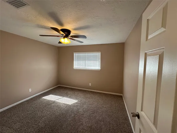 an empty room with windows and fan