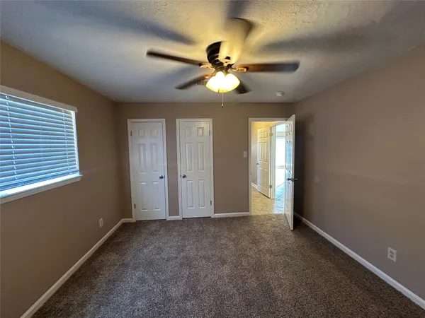 a view of an empty room and window and chandelier fan
