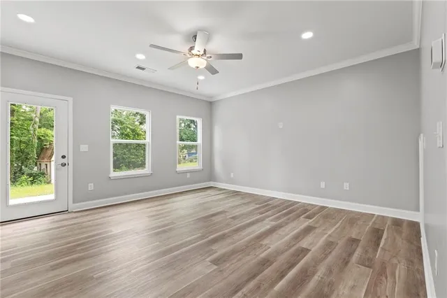 an empty room with wooden floor fan and windows