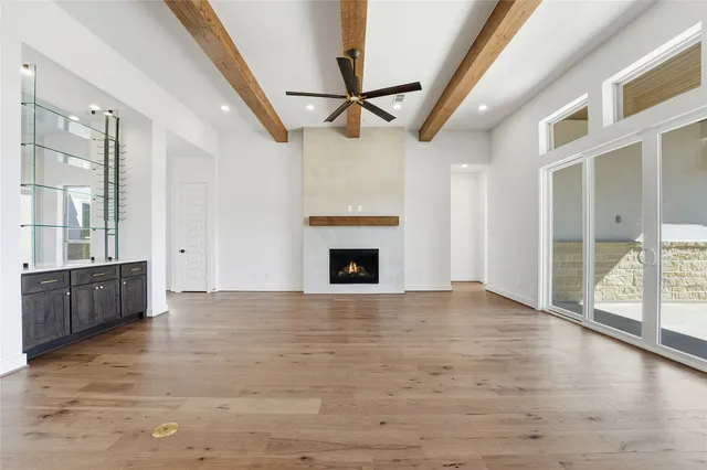 a view of an empty room with wooden floor and a fireplace
