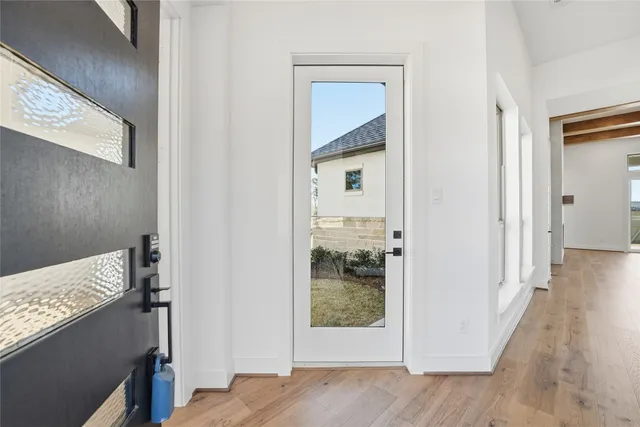 a view of a hallway with wooden floor and a bathroom