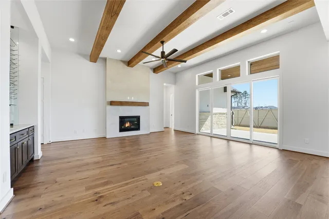 a view of an empty room with wooden floor and a fireplace