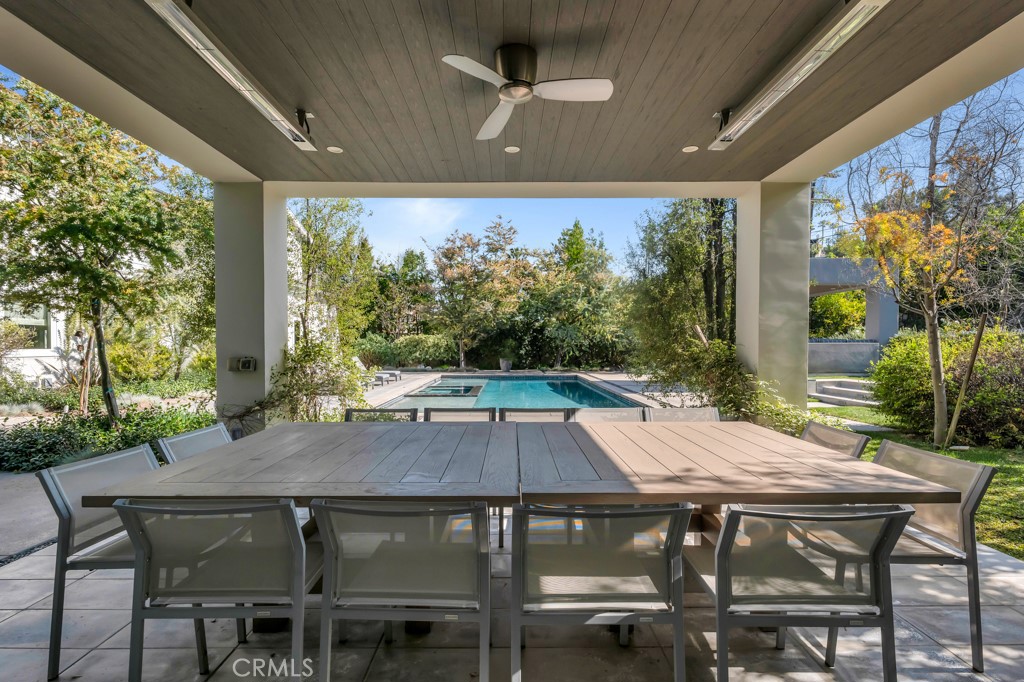 17950 Rancho Street Encino, CA 91316 - Photo 59 of 75 a view of a patio with table and chairs under an umbrella with a small yard