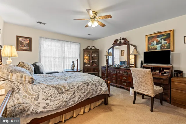 a bedroom with a bed a computer on desk and a dresser
