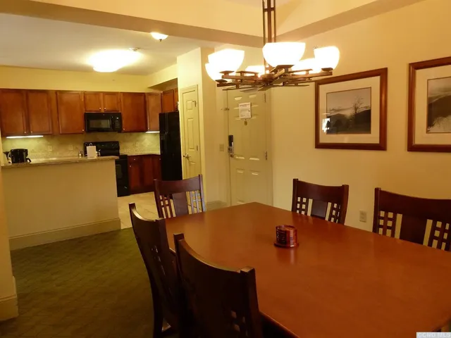 a kitchen with stainless steel appliances a dining table chairs and a refrigerator