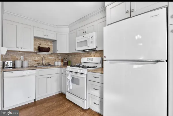 a kitchen with white cabinets and white appliances