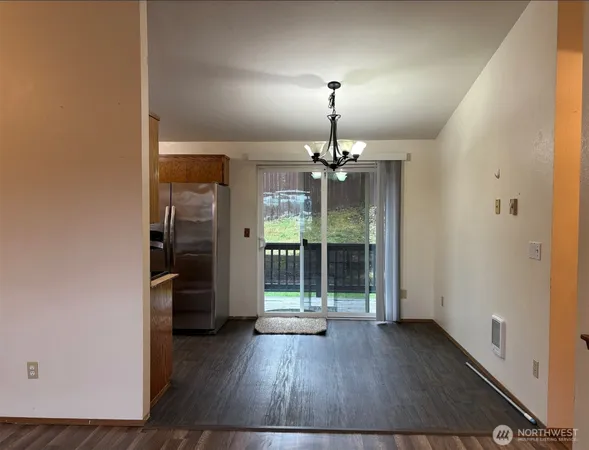 an empty room with wooden floor chandelier and entryway
