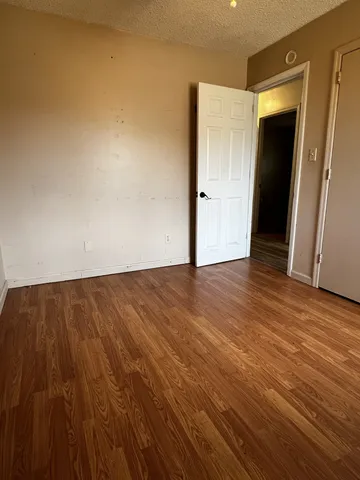 a view of an empty room with wooden floor and closet