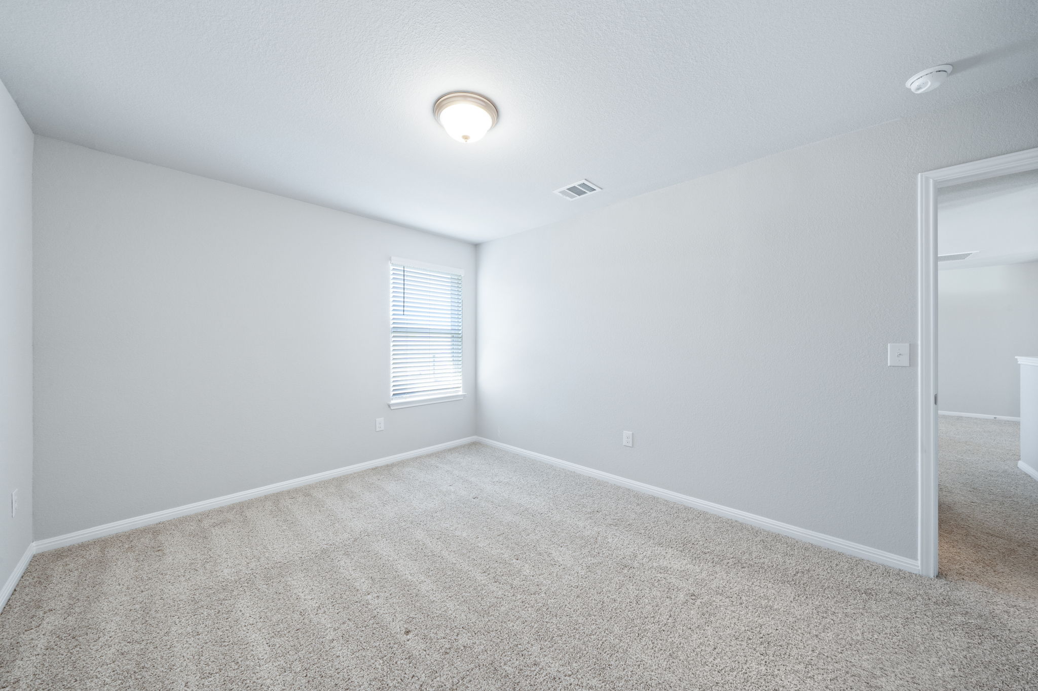 2412 Starhill Ranch Street Georgetown, TX 78628 - Photo 36 of 40 A well-proportioned bedroom with plush carpeting and natural light from a window with blinds.