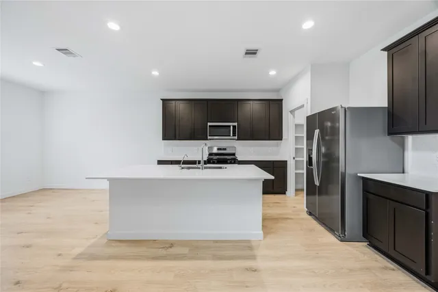 a large kitchen with a large counter top stainless steel appliances and cabinets
