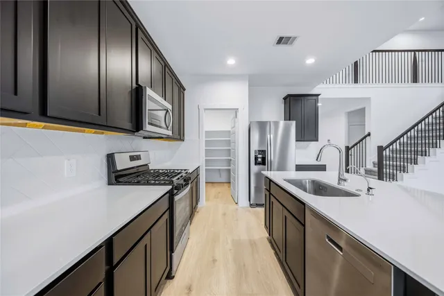 a kitchen with stainless steel appliances granite countertop a sink a stove and a refrigerator