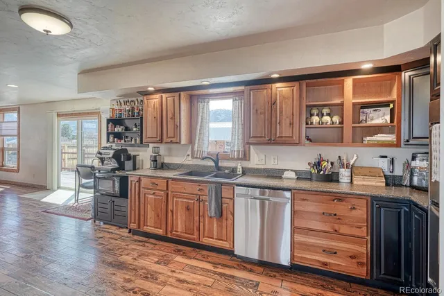 a kitchen with stainless steel appliances granite countertop a stove a sink dishwasher and a microwave oven with wooden cabinets