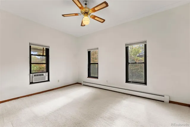 an empty room with windows and fan