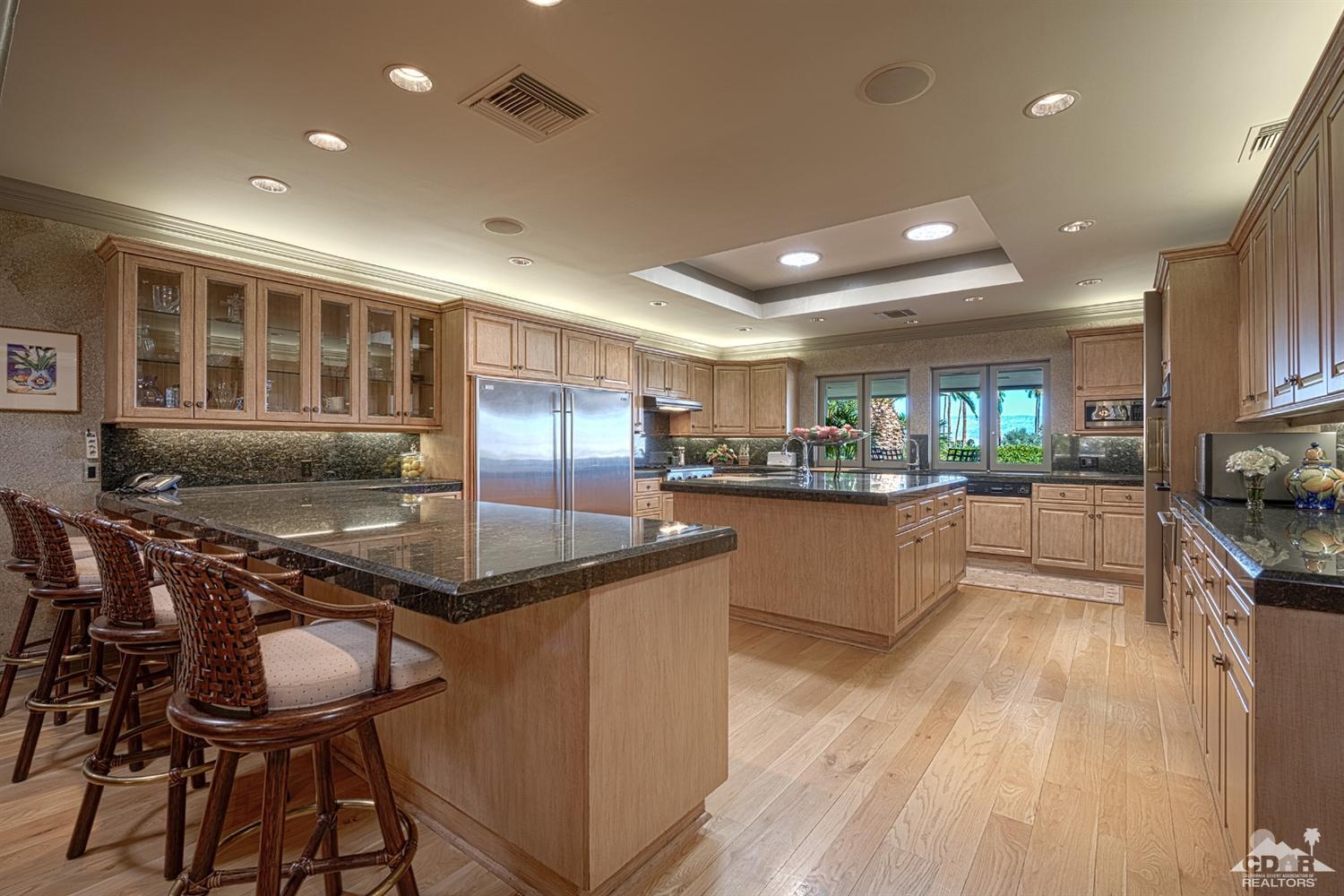 70375 Thunderbird Road Rancho Mirage, CA 92270 - Photo 13 of 54 a kitchen with stainless steel appliances granite countertop a stove top oven a sink a dining table and chairs with wooden floor