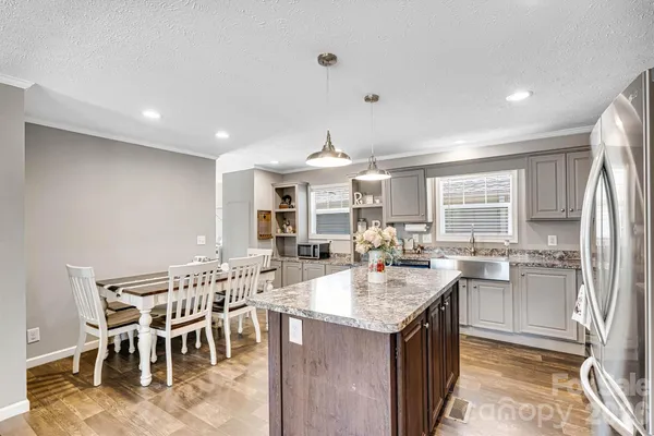a kitchen with stainless steel appliances granite countertop a refrigerator oven a sink dishwasher and white cabinets with wooden floor