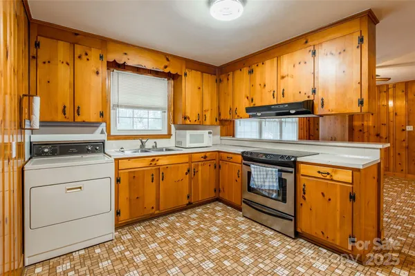 a kitchen with granite countertop a refrigerator a stove and wooden cabinets