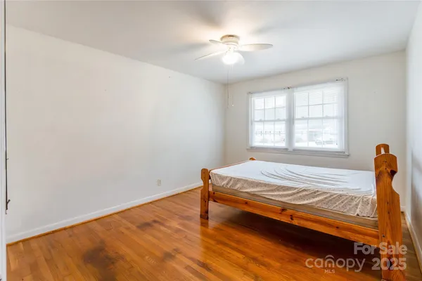 a bedroom with a bed and a window with wooden floor
