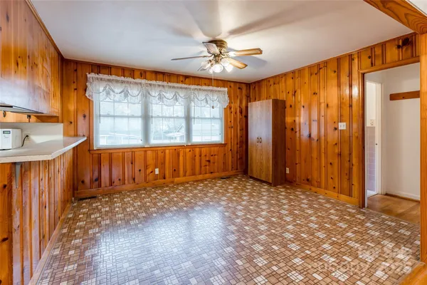 an empty room with chandelier fan and windows