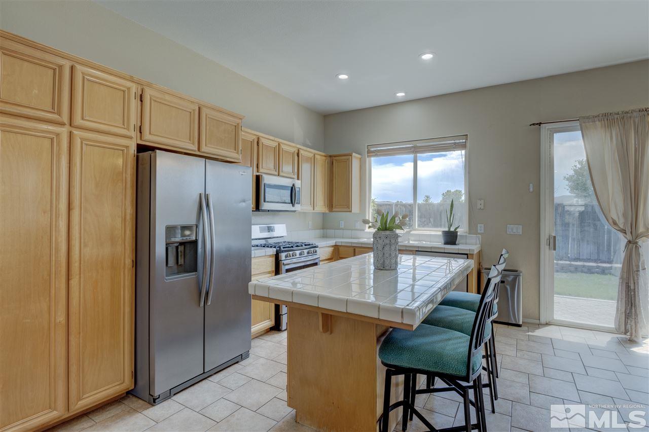 1660 Cattlemen Court Reno, NV 89521 - Photo 8 of 21 a kitchen with stainless steel appliances granite countertop a refrigerator a sink dishwasher a dining table and chairs with wooden floor
