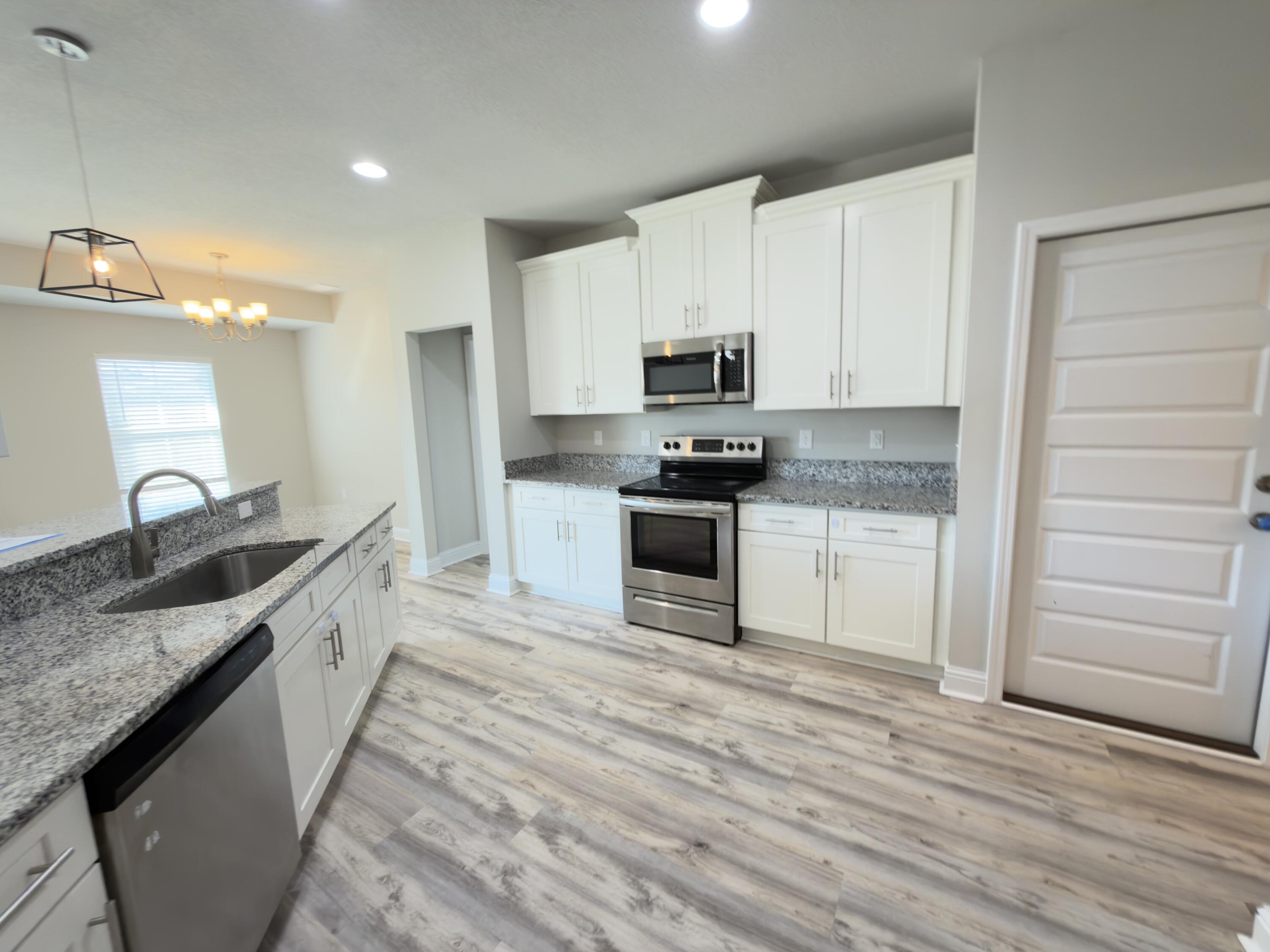 5281 Moore Loop Crestview, FL 32536 - Photo 3 of 28 a large kitchen with kitchen island granite countertop a stove top oven a sink a counter space and cabinets