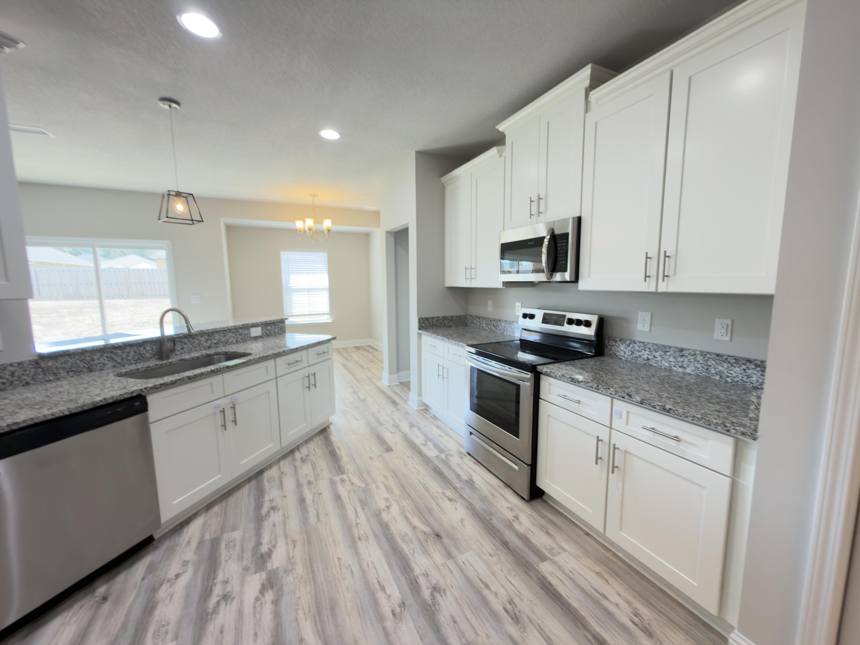 5281 Moore Loop Crestview, FL 32536 - Photo 4 of 28 a kitchen with granite countertop white cabinets and black appliances