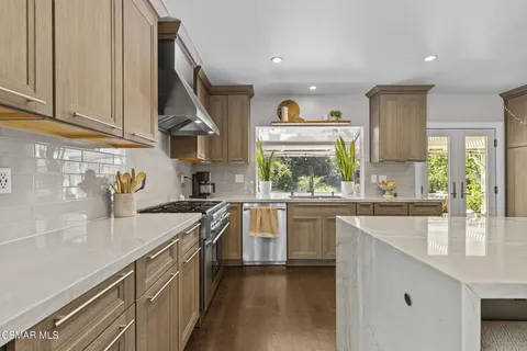 a kitchen with stainless steel appliances granite countertop a sink a stove and a wooden floors