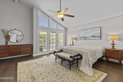 a bedroom with a bed a mirror on dresser and a table